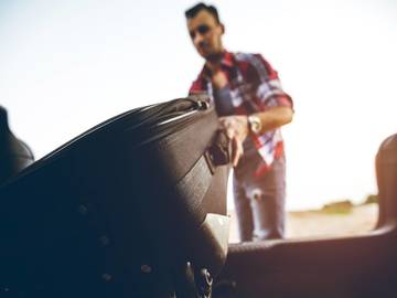 man putting suitcase into trunk